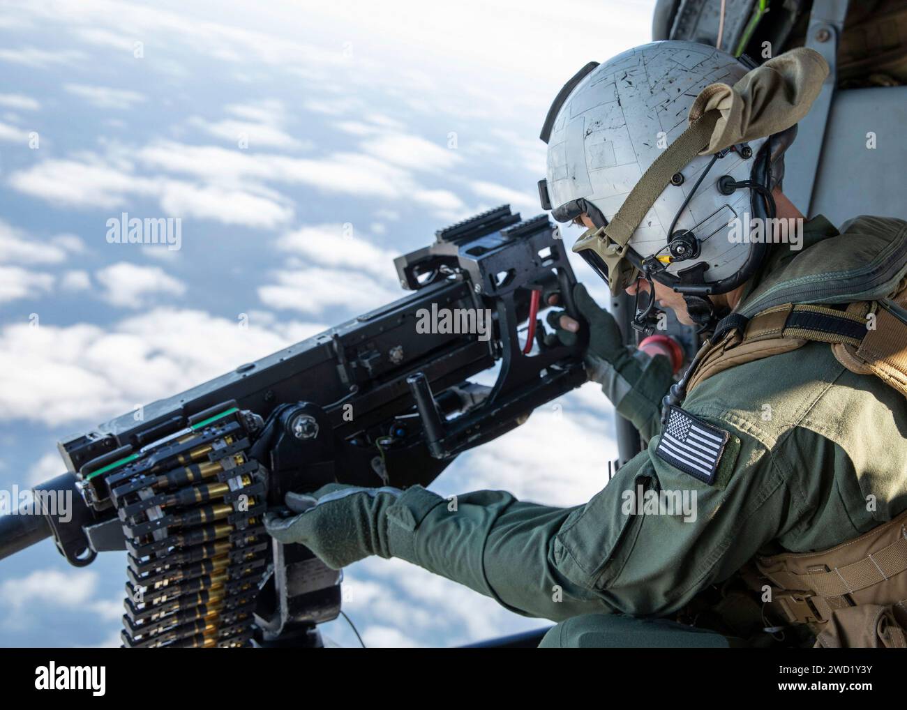 Naval Air Crewman adjusts a .50-caliber machine gun in an MH-60S Sea Hawk helicopter. Stock Photo