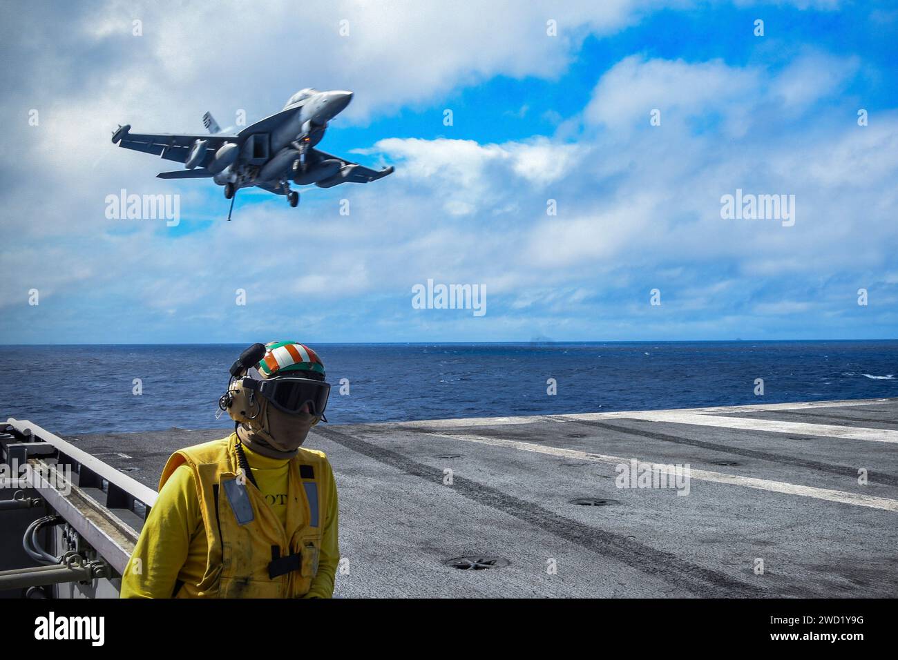 Airman observes the flight deck as an E/A-18G Growler prepares to land on USS Ronald Reagan. Stock Photo
