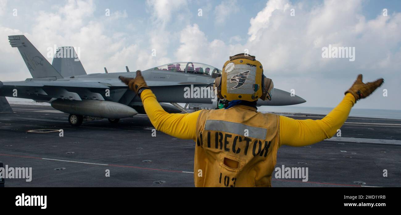 Sailor directs an E/A-18G Growler on the flight deck of the aircraft carrier USS Nimitz. Stock Photo