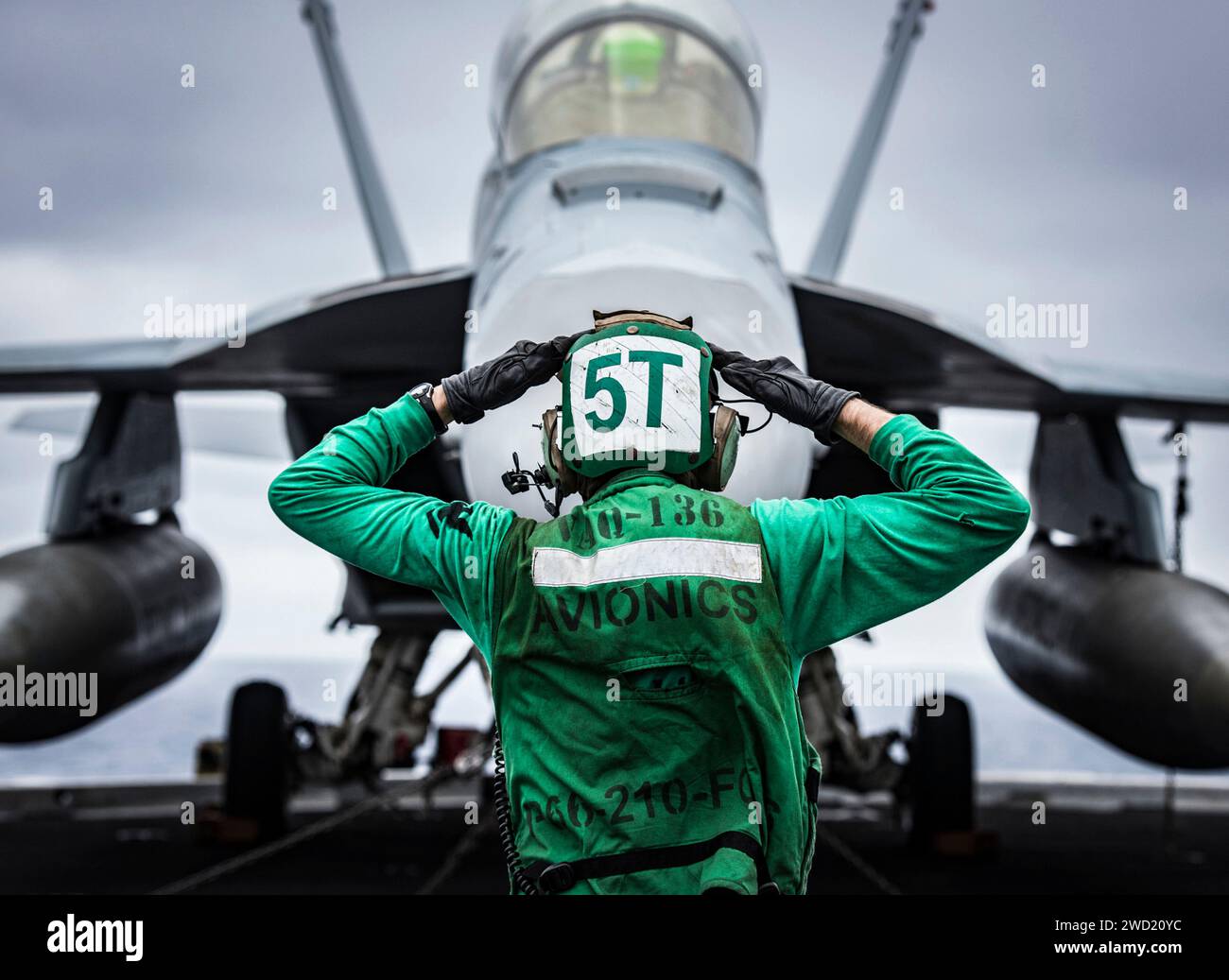 U.S. Navy Aviation Electronics Technician signals to the crew of an EA-18G Growler. Stock Photo