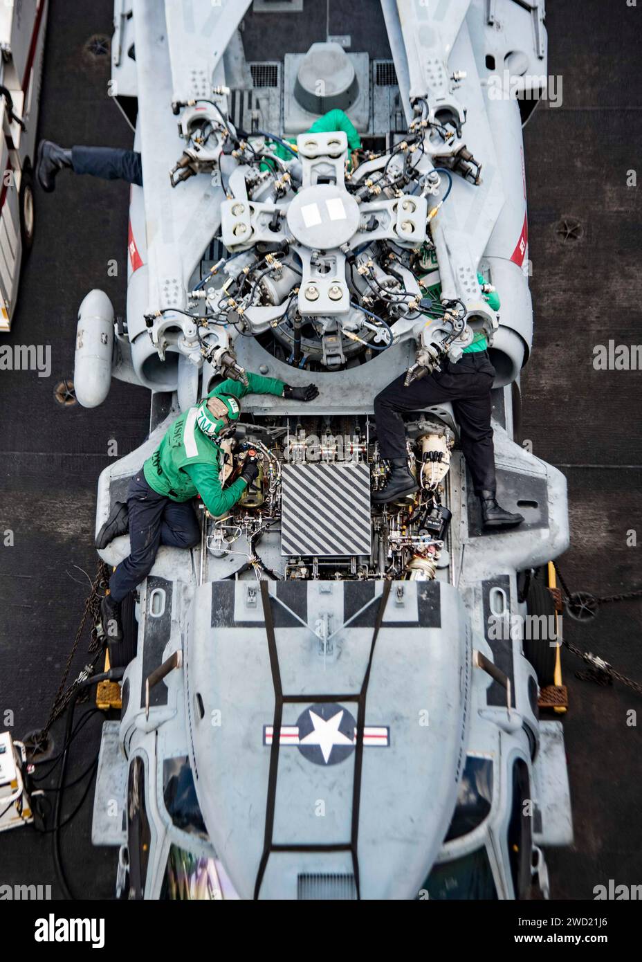 Sailors conduct maintenance on an MH-60S Sea Hawk helicopter. Stock Photo