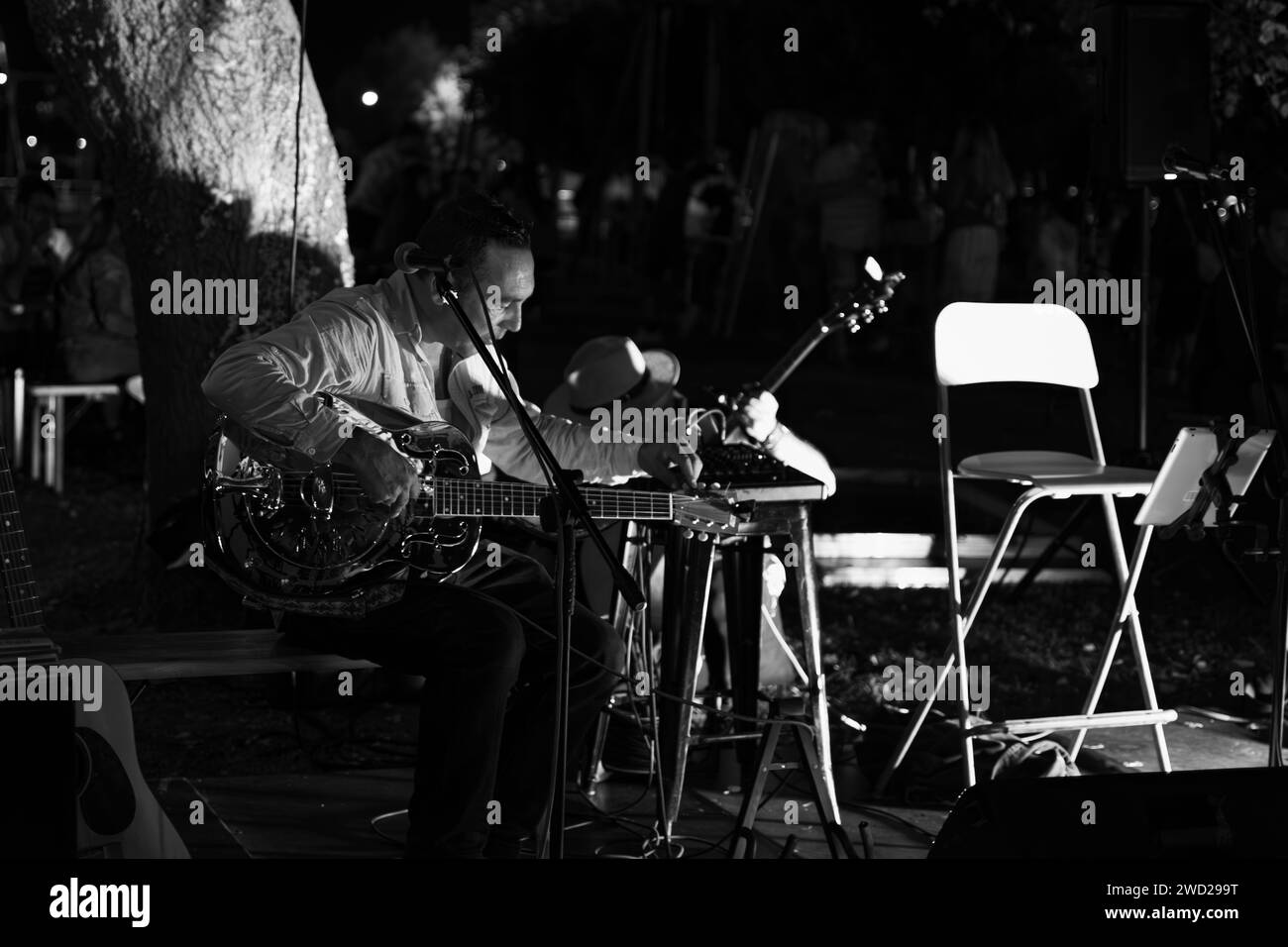 Seated guitarist playing guitar at a beer party, black and white Stock Photo