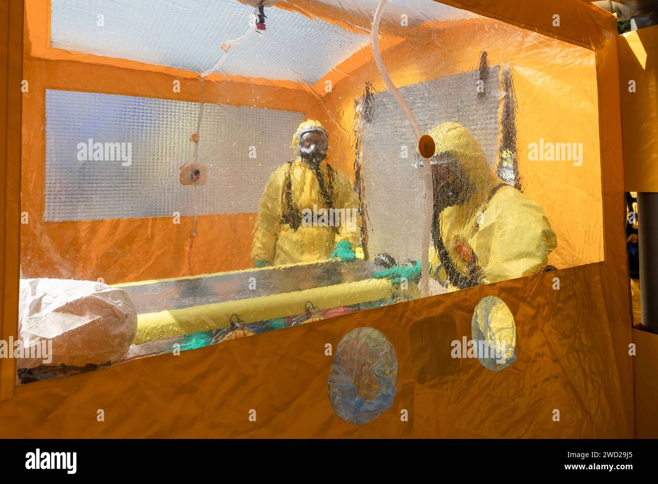 Selective focus on decontamination tent. Biohazard team of emergency medical service in protective suits. Stock Photo