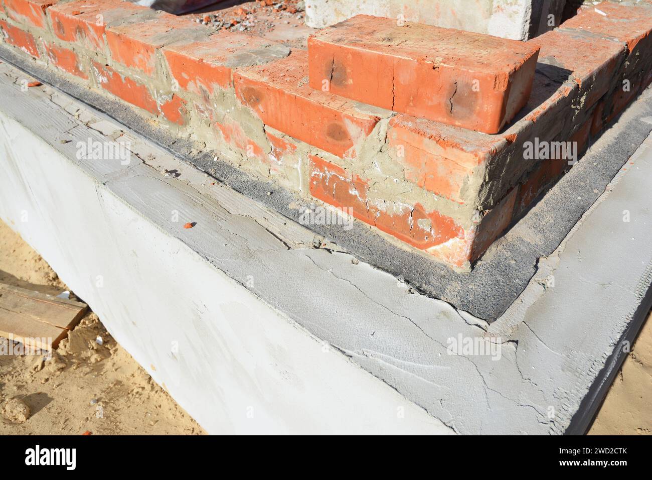 Laying a brick wall above the insulated foundation with a dampproof