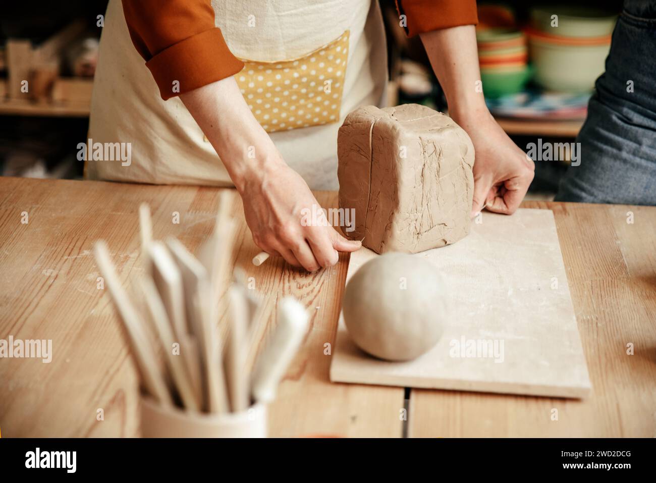 Potter cuts large piece of clay into pieces with string Stock Photo