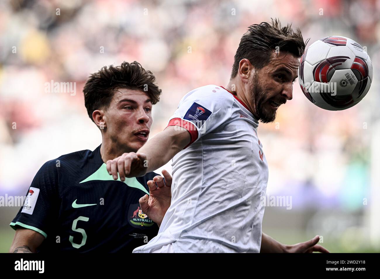 Doha, Qatar. 18th Jan, 2024. Syria's Mouaiad Alajaan (R) vies with Australia's Jordan Bos during the Group B match between Syria and Australia at AFC Asian Cup Qatar 2023 in Doha, Qatar, Jan. 18, 2024. Credit: Jiang Han/Xinhua/Alamy Live News Stock Photo