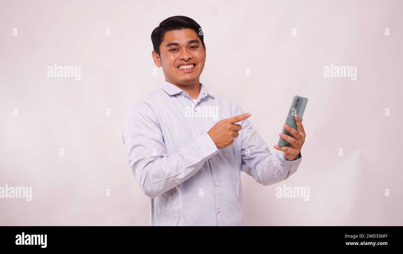 Asian man clenched fist showing excitement when looking to his phone on white background Stock Photo
