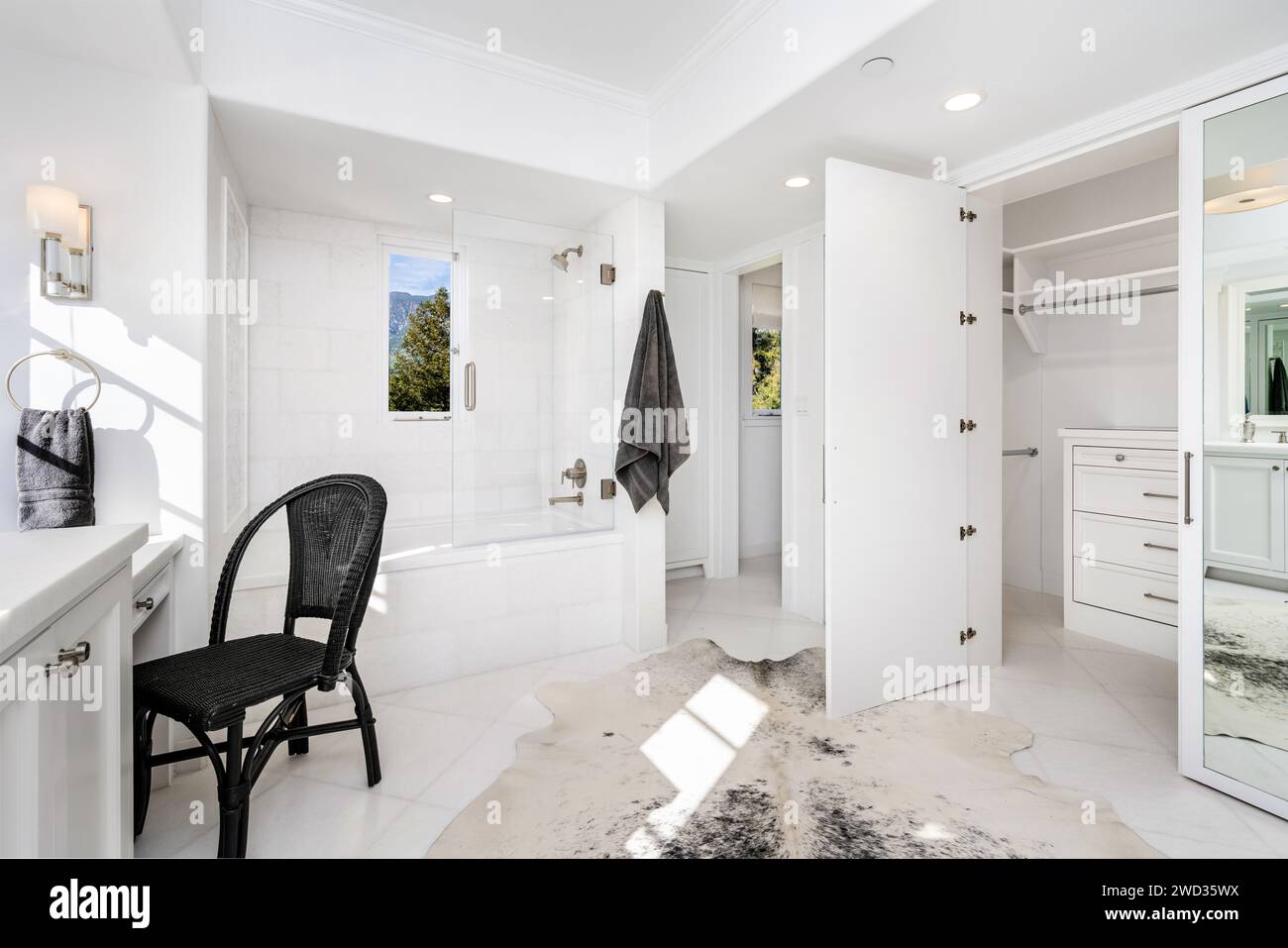 A large white bathroom with toilet, vanity, closet, and mirror Stock Photo