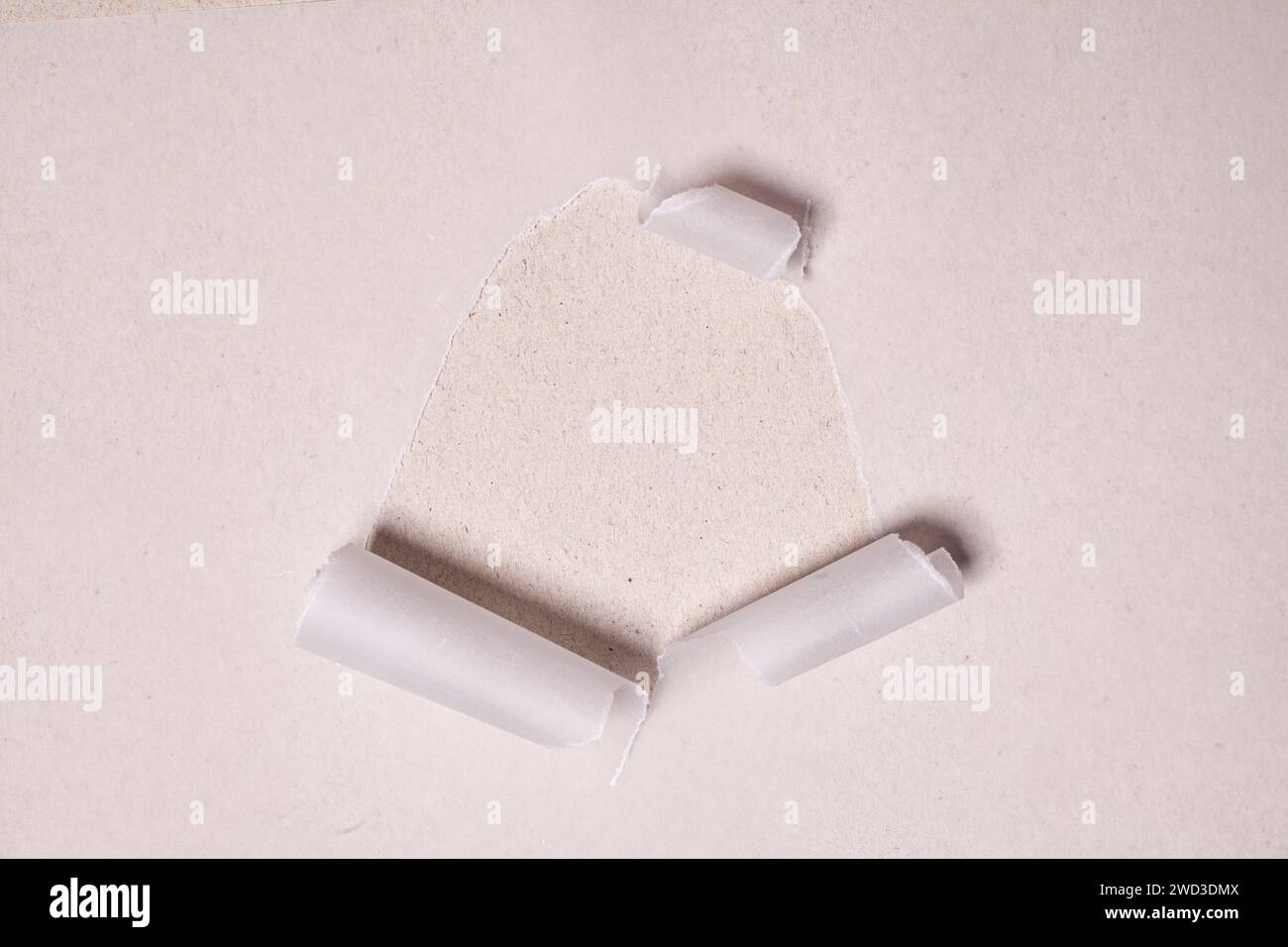 Torn paper with opening showing cardboard paper background. Stock Photo
