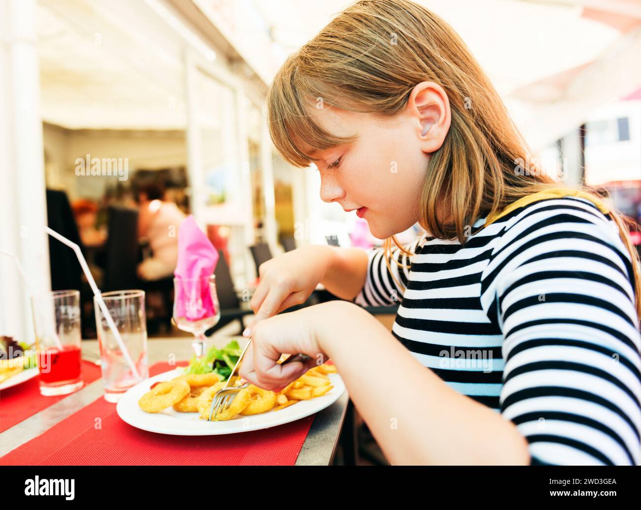 Child eating for lunch calamares a La Romana Fried Squid at restaurant