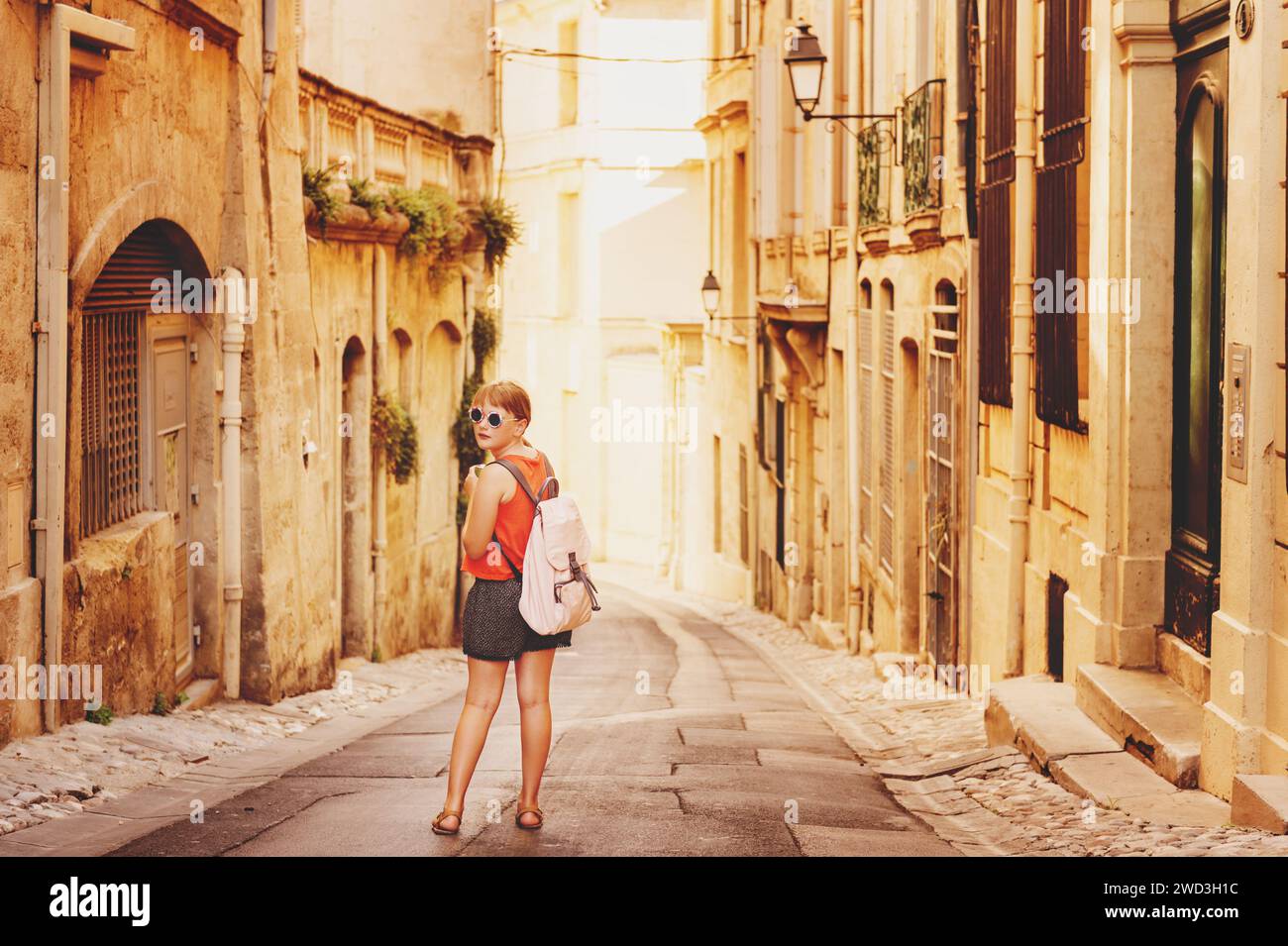 Funny little girl traveler walking on the streets of Provence, wearing backpack. Travel with kids, family vacation on south of France, image taken in Stock Photo