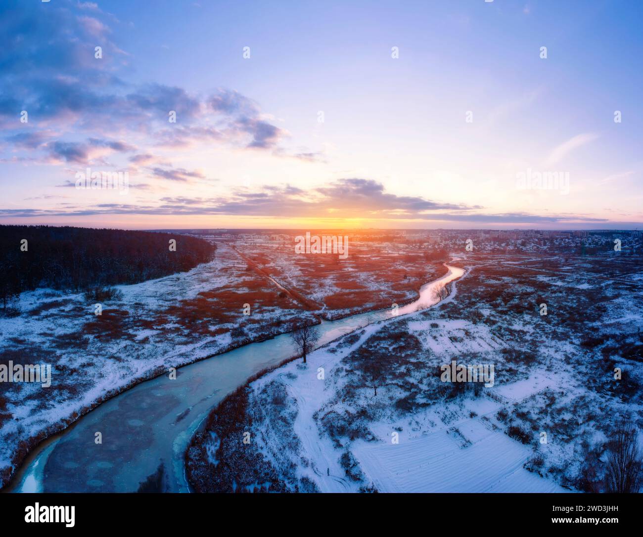 Winter landscape with winding frozen river in field covered in snow ...