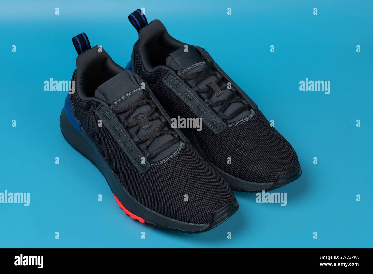 Black sport run shoes with laces perspective view isolated on blue studio background Stock Photo