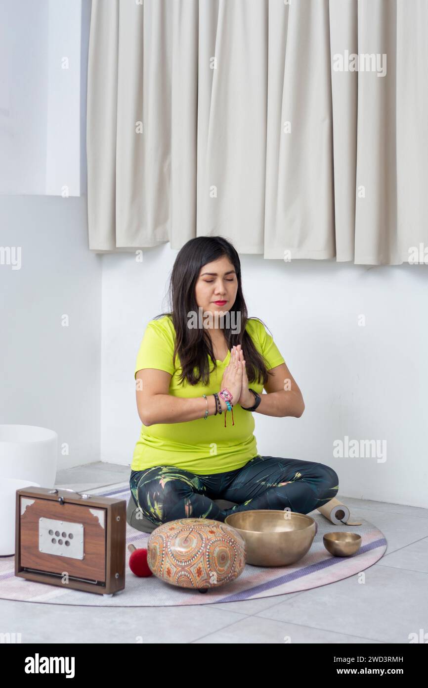 Vertical photo of a Latin woman meditating sitting on the floor of a ...