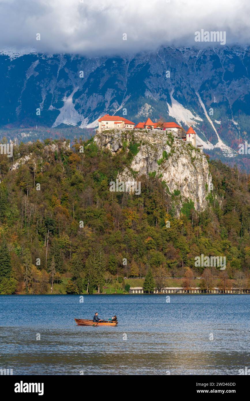 A serene boat glides along the calm waters, with a majestic castle nestled atop a scenic cliff in the background Stock Photo