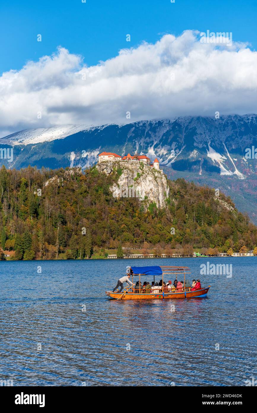 A lone tourist boat is peacefully floating on a serene lake under a castle in Bled, Slovenia Stock Photo