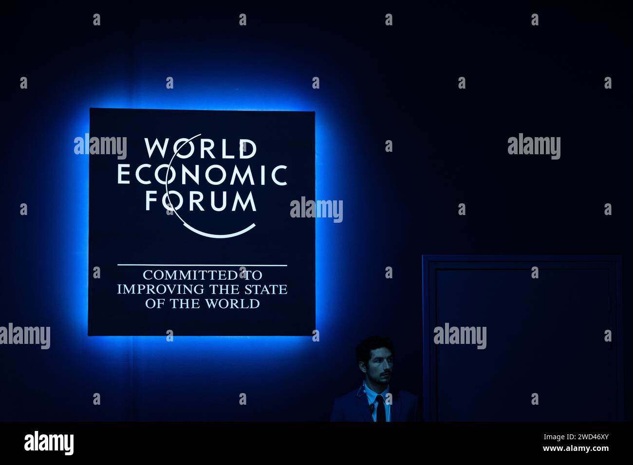 Davos, Switzerland. 18th Jan, 2024. A man stands under a World Economic Forum sign. The annual meeting of the World Economic Forum is regarded as one of the most important meeting places for top politicians, top managers and scientists. Debates and confidential meetings focus on solutions to global challenges. Credit: Hannes P. Albert/dpa/Alamy Live News Stock Photo