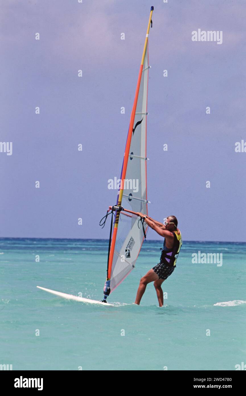 Young man windsurfing (boardsailing) in the blue waters off of Aruba ca