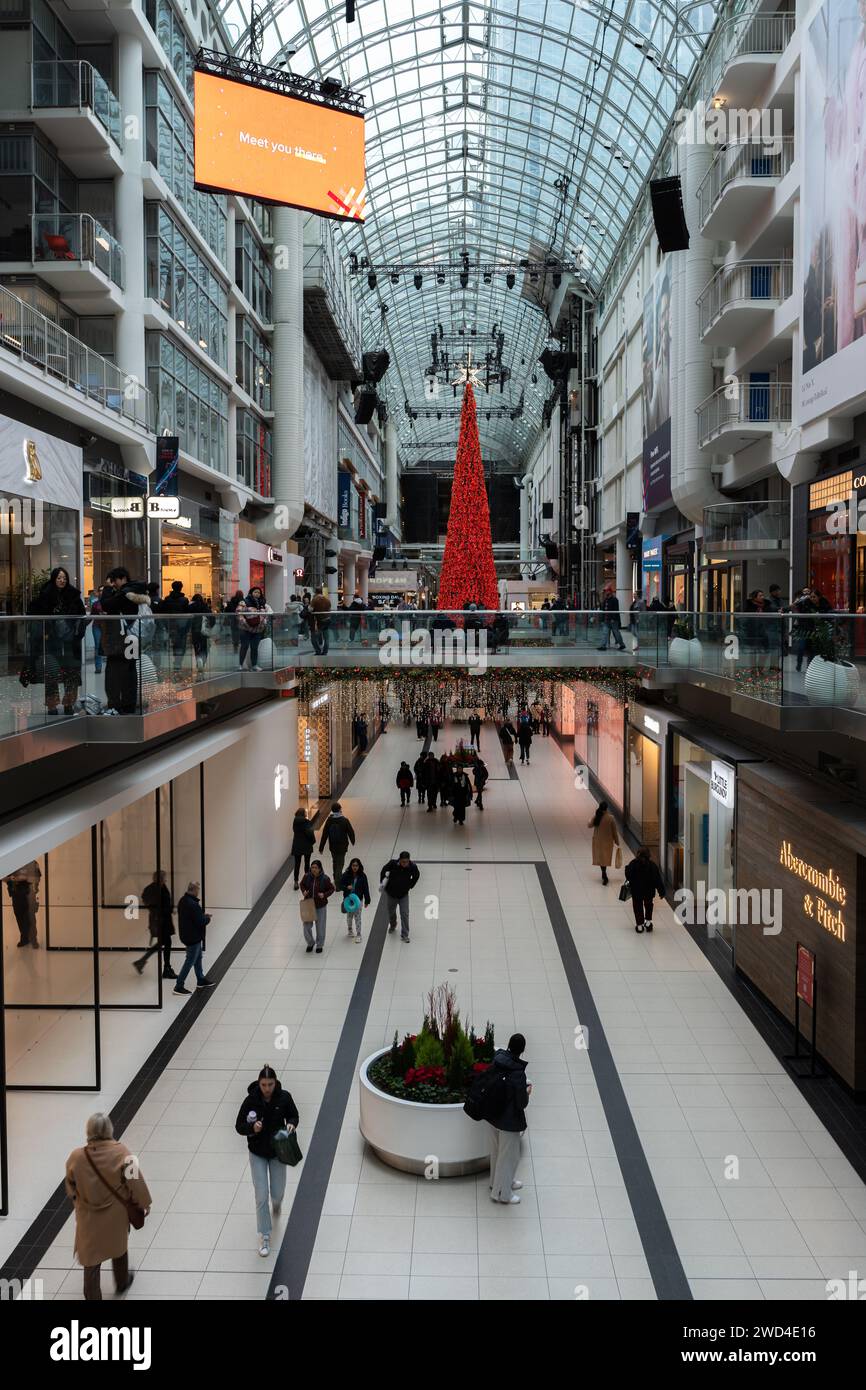 Large crowd walking through a shopping mall adorned with festive Christmas decorations Stock Photo