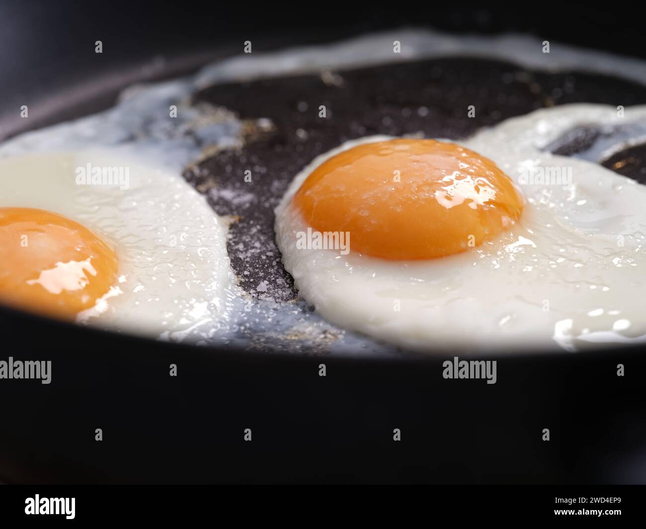 Two fried eggs seasoned with sea salt in a frying pan. Close up. Stock Photo