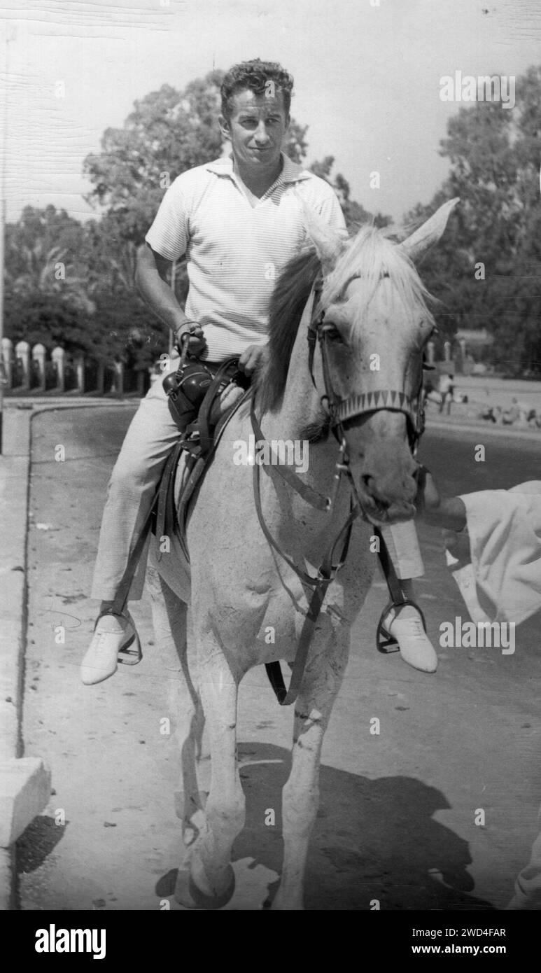 Antique photo of a man in a white polo shirt and light shorts sitting astride a horse. Germany. Date unknown circa 1960s Stock Photo Alamy