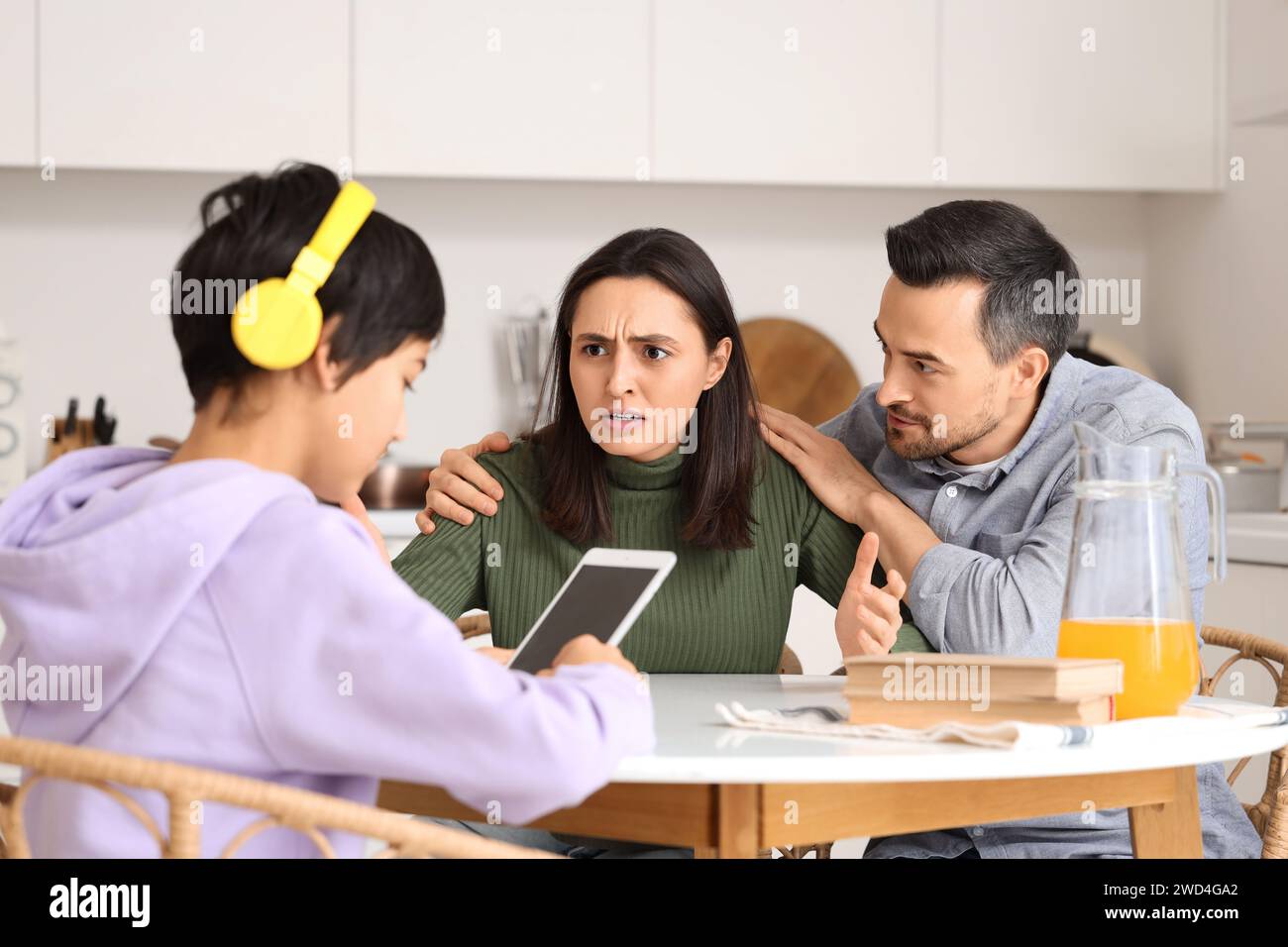 Upset parents with their teenage son at table in kitchen. Family