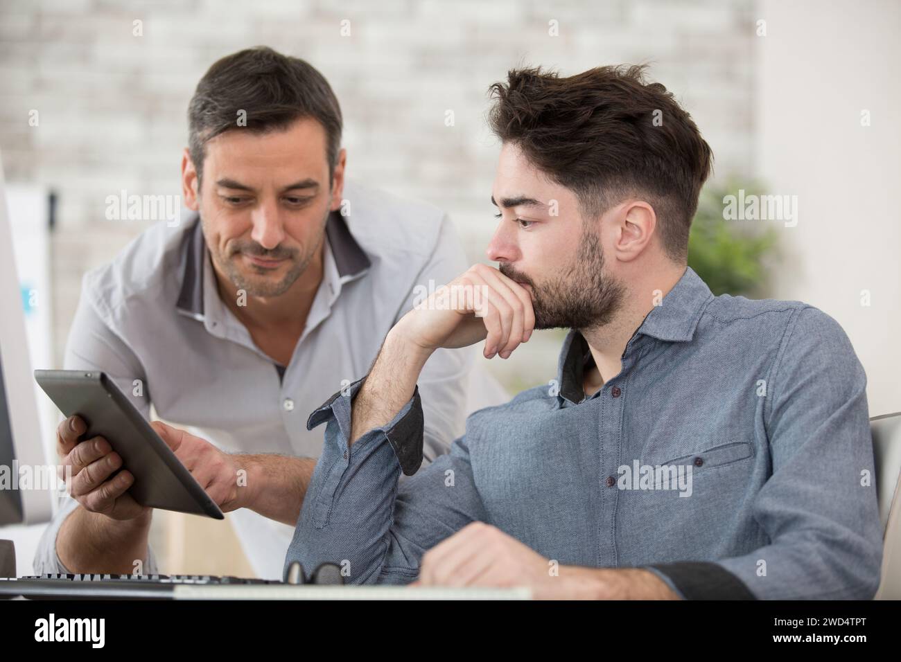 diverse businessmen talking using digital tablet sit at office desk Stock Photo