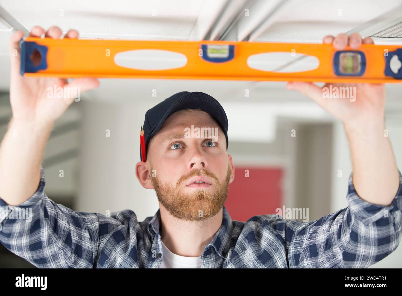 house renovation worker checking the alignment of a ceiling Stock Photo