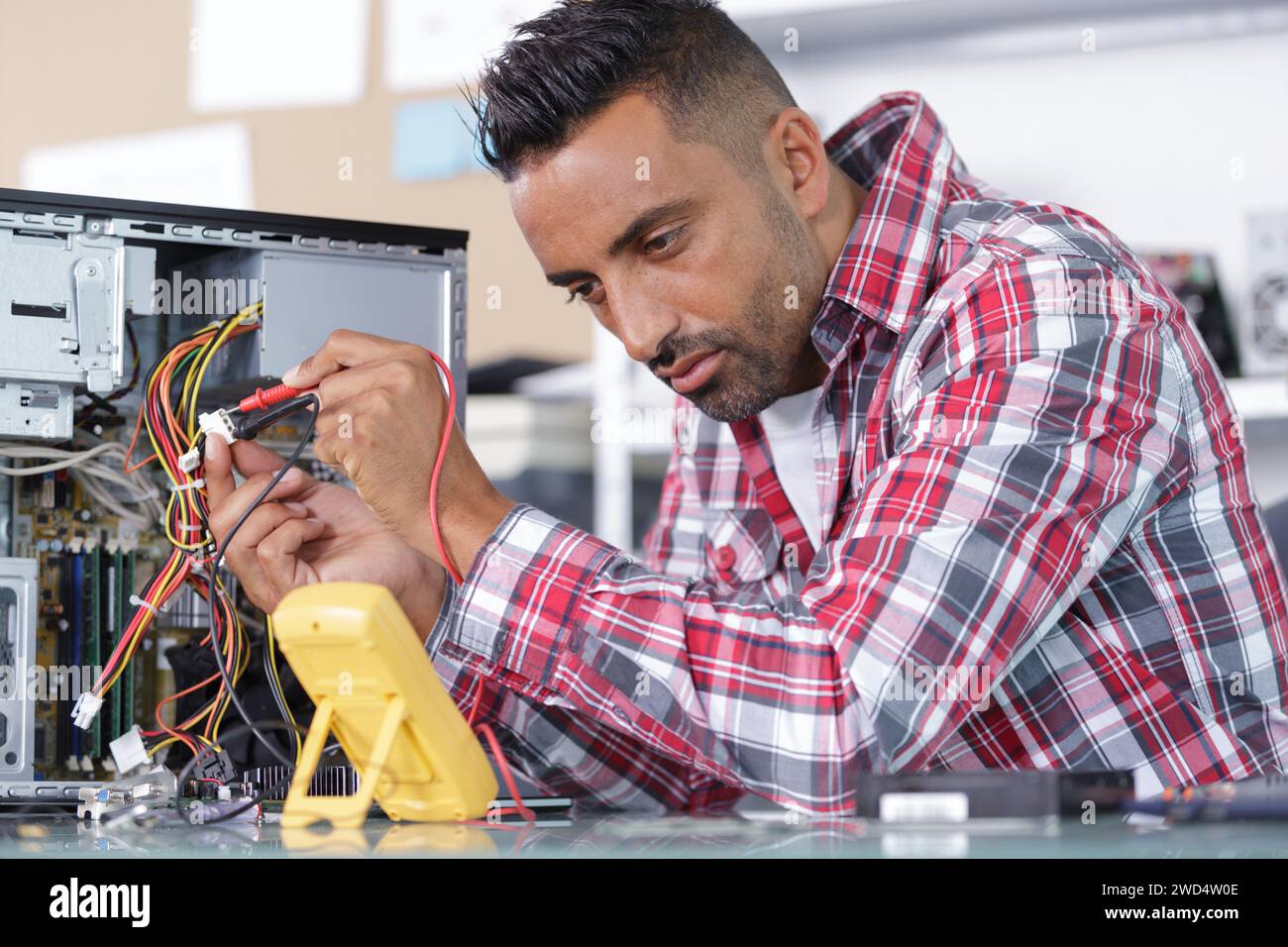 man uses a multimeter voltmeter to check a pc Stock Photo