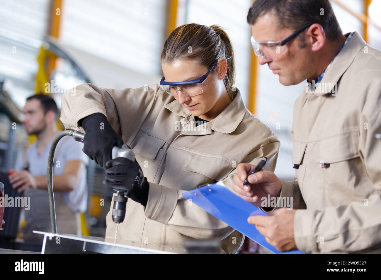 female apprentice engineer working on drill in factory Stock Photo