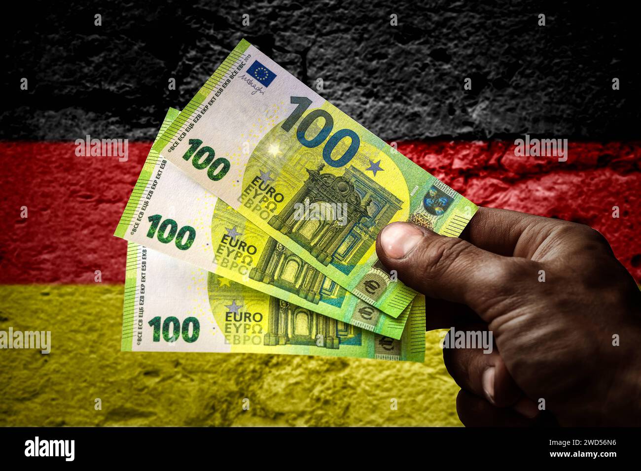 January 18, 2024: Hand of an asylum seeker holding several hundred euro banknotes in front of a Germany flag. Symbolic image of money and benefits in kind for refugees PHOTOMONTAGE *** Hand von einem Asylbewerber hält mehrere hundert Euro Geldscheine vor einer Deutschland Flagge. Symbolbild Geld und Sachleistungen für Geflüchtete FOTOMONTAGE Stock Photo