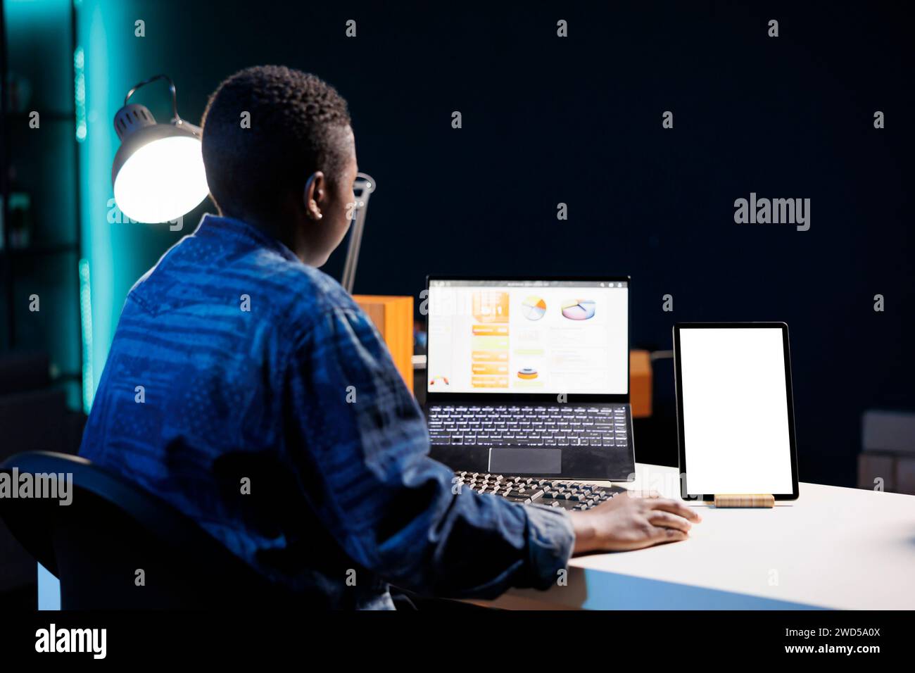 While browsing on laptop, african american woman sits at desk with ...