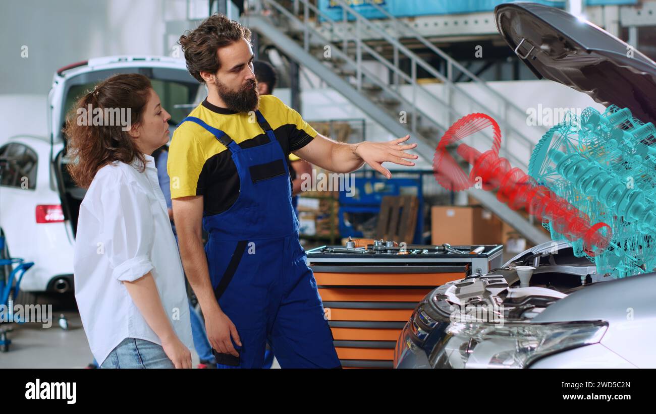 Adept technician in repair shop using holographic augmented reality to show customer damaged piston inside car motor. Garage specialist using advanced AR tech to project automobile parts for woman Stock Photo
