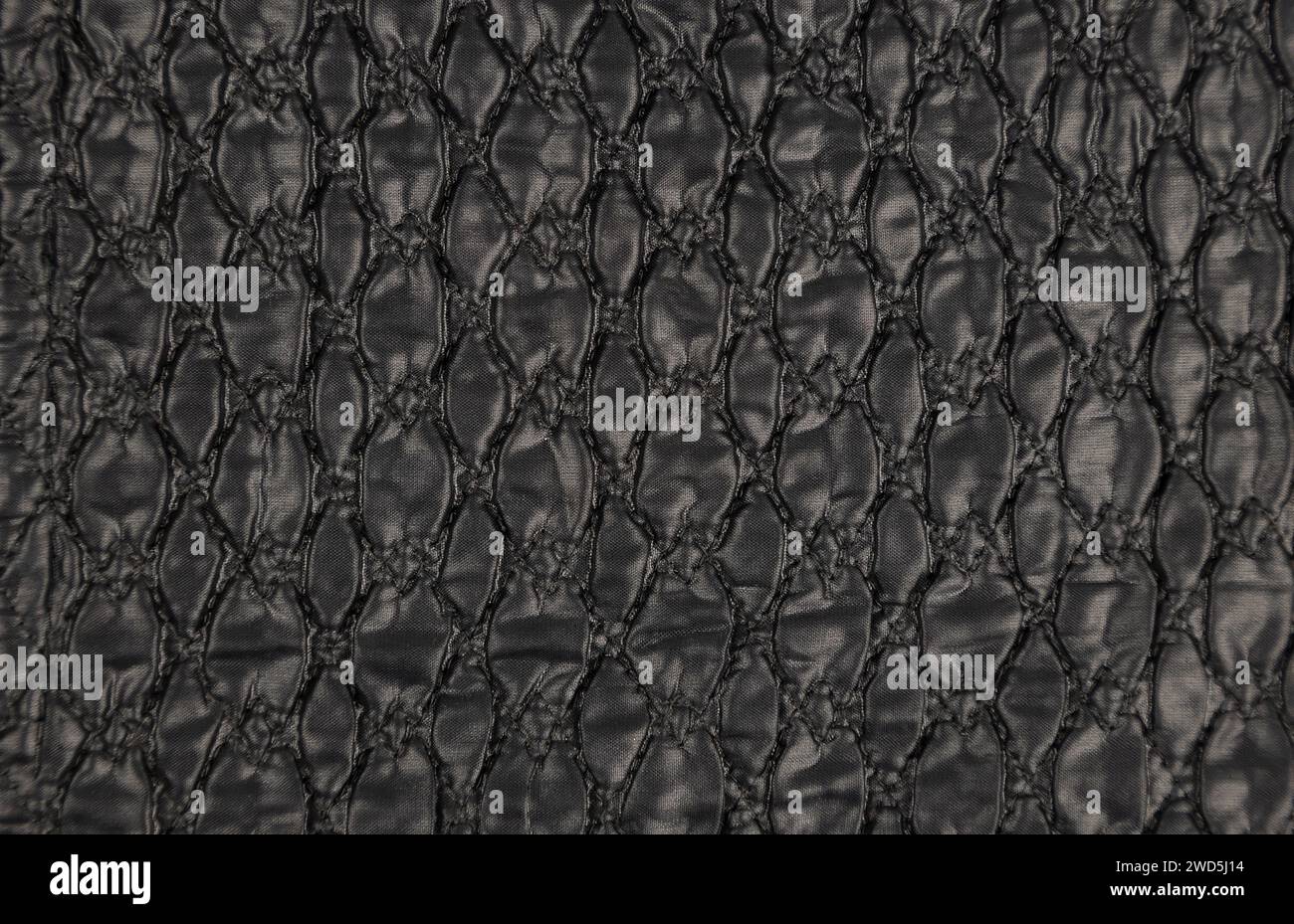 A pattern on a black leather surface. Black leather texture background close-up. Stock Photo