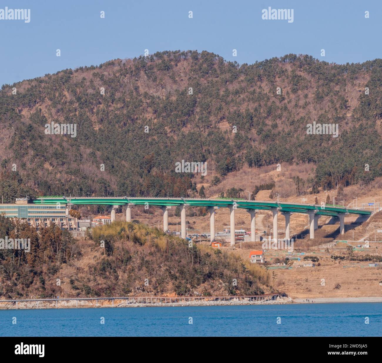 Ocean Landscape with a green bridge spanning a valley and a mountain in the background, South Korea Stock Photo