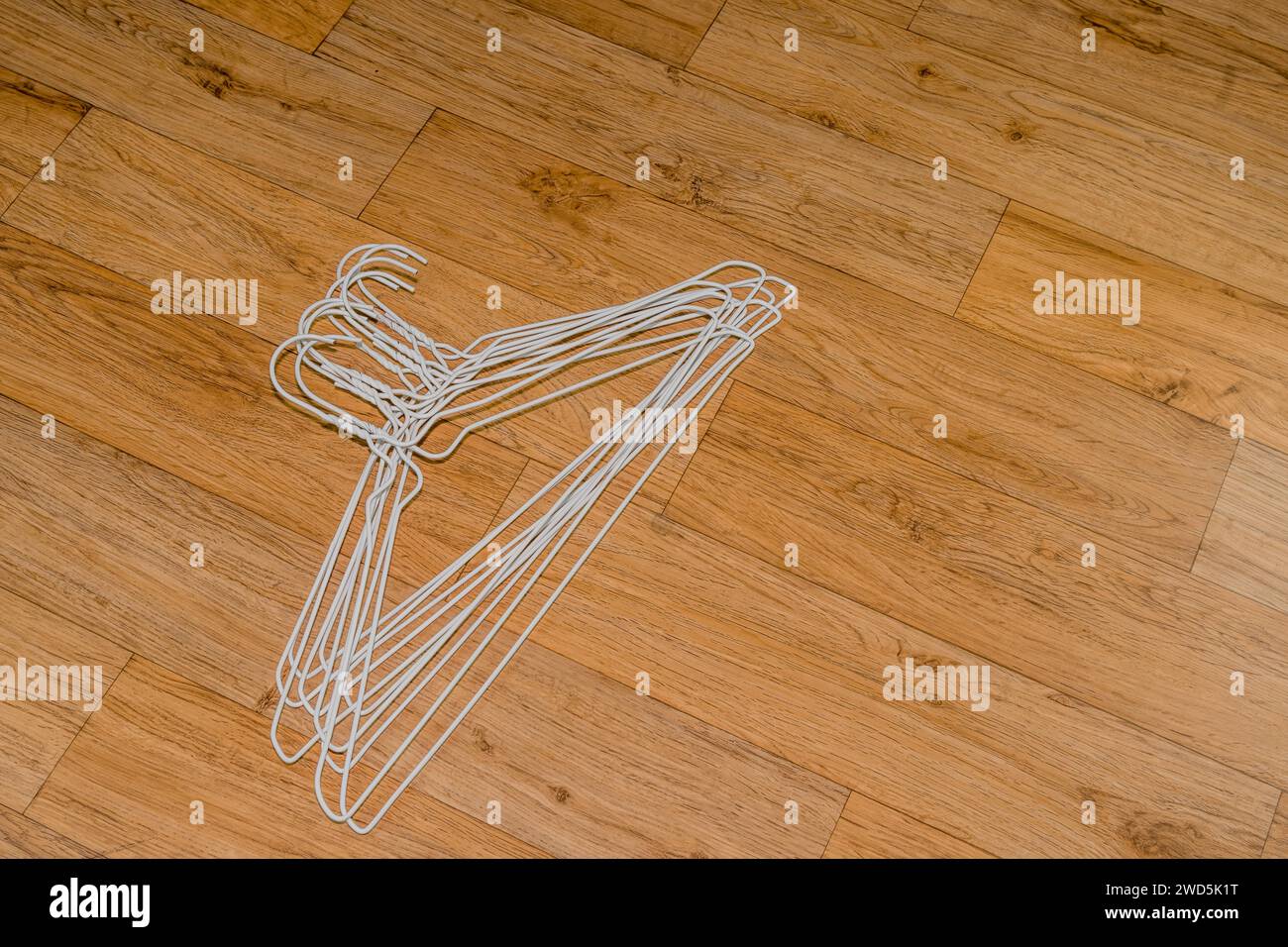 Stack of white wire clothes hangers laying on wood grain background, South Korea Stock Photo