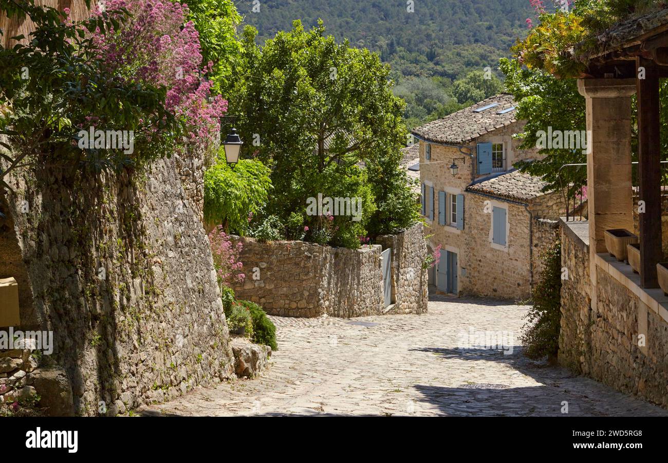 Steep cobbled street with walls and houses made of natural stone with a ...