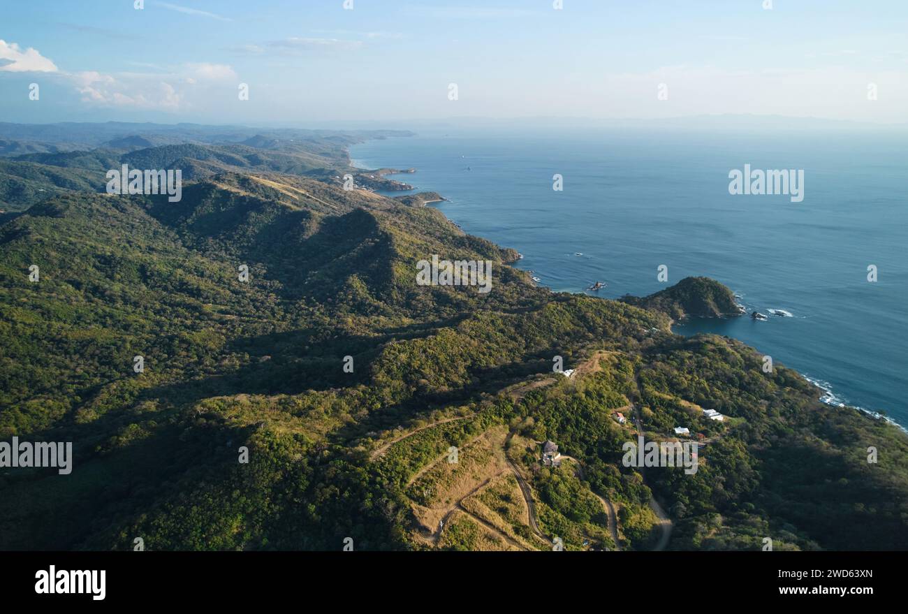 Seaside coastline with green hills and houses aerial drone view Stock Photo