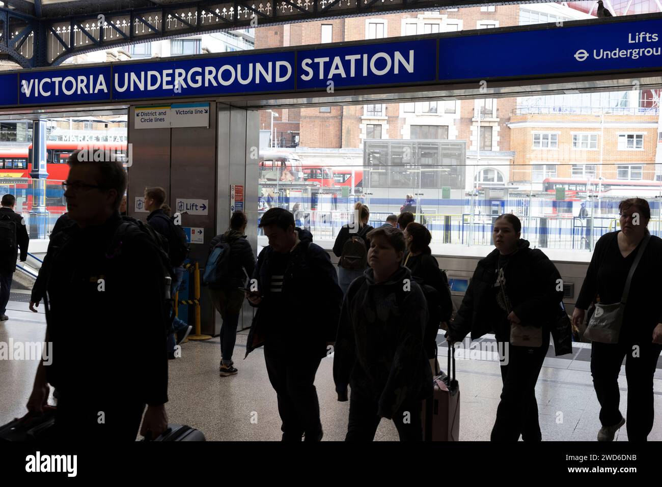 A busy entrance and exit to Victoria Underground Station with the railway station behind where
