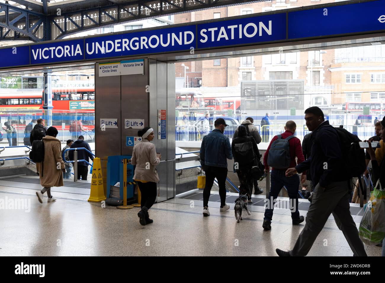 A busy entrance and exit to Victoria Underground Station with the railway station behind where