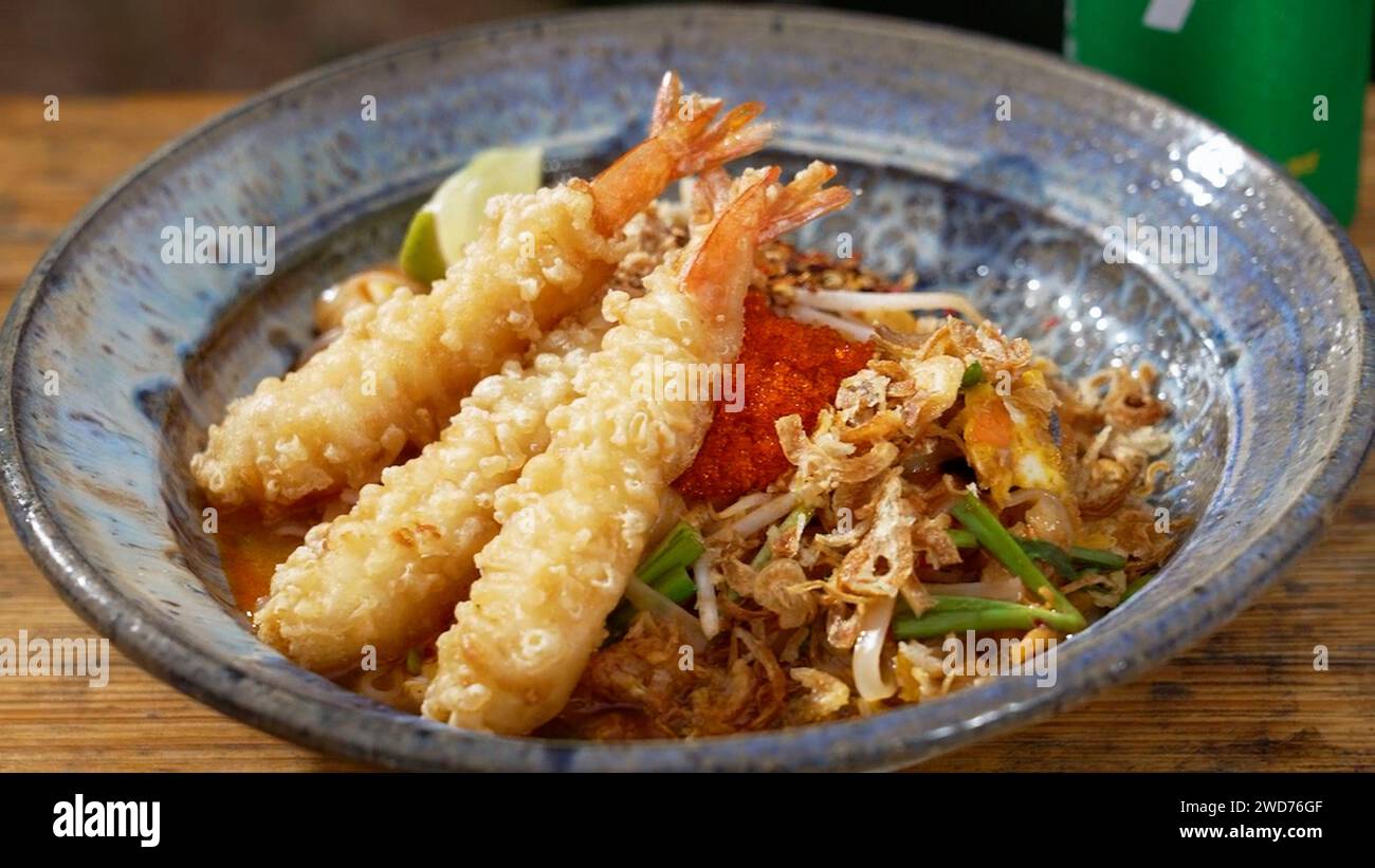 A closeup of a bowl of Shrimp Pad on a wooden table Stock Photo
