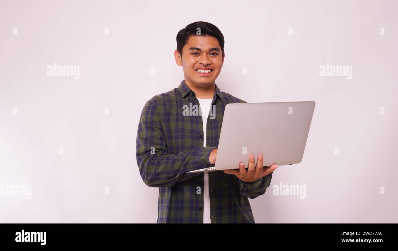 Asian student standing on studio while using laptop against white background Stock Photo
