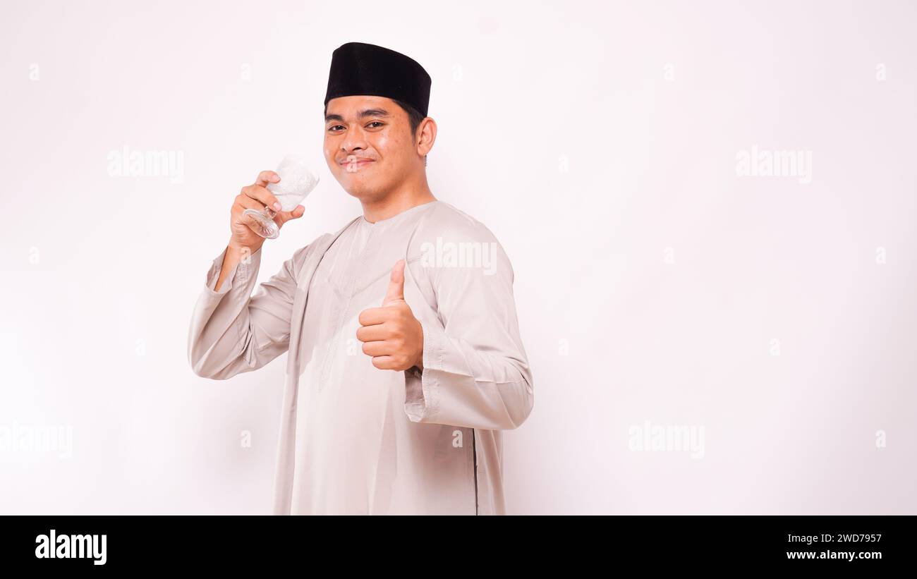 Asian muslim man break the fasting with drinking water during month of Ramadan. Isolated on white background Stock Photo