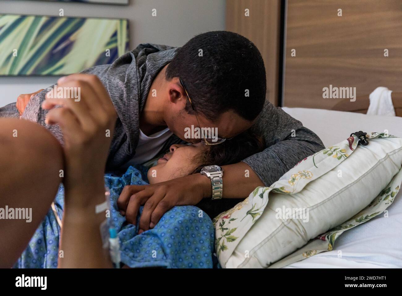 Multiracial couple kissing and crying after giving birth Stock Photo