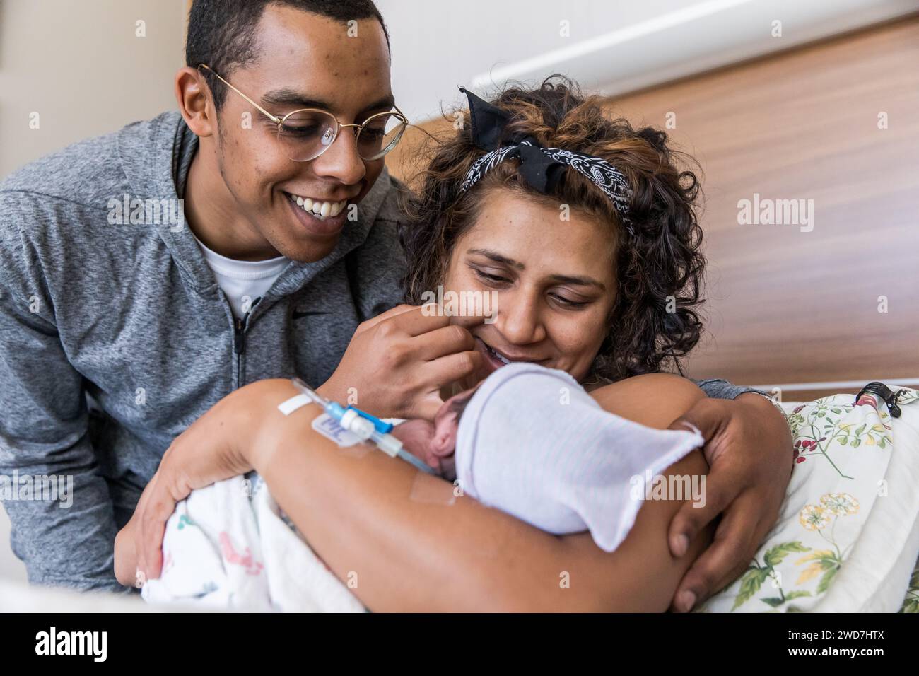 Multiracial couple smiles at brand new baby right after giving birth Stock Photo