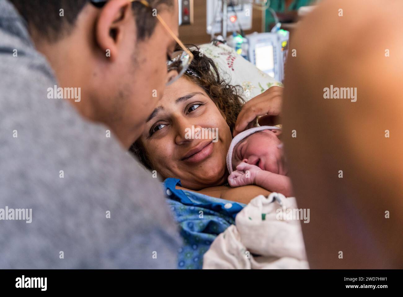 Indian mom smiling at dad after giving birth in hospital Stock Photo