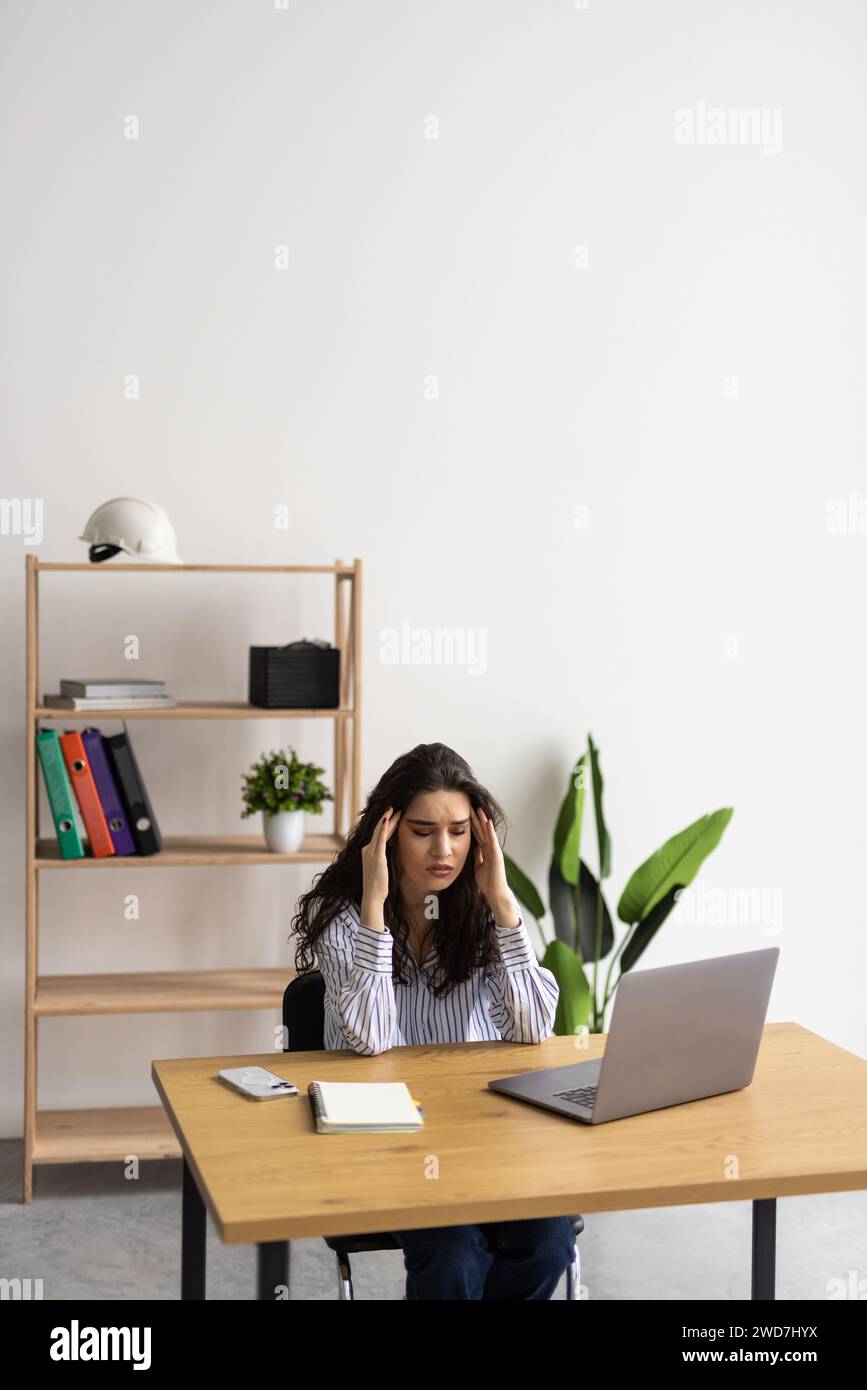 Young attractive woman at modern office desk, working on laptop