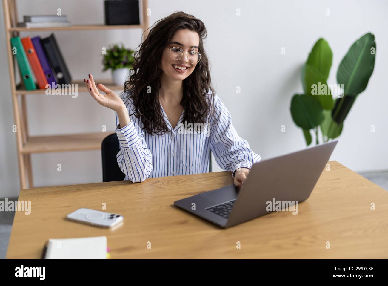 Young customer service representative wearing headset doing video call on laptop at office Stock Photo
