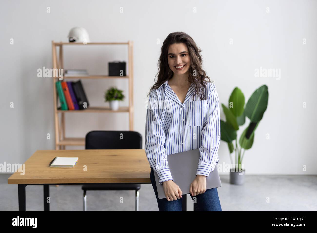 Smiling businesswoman holding open laptop in office Stock Photo