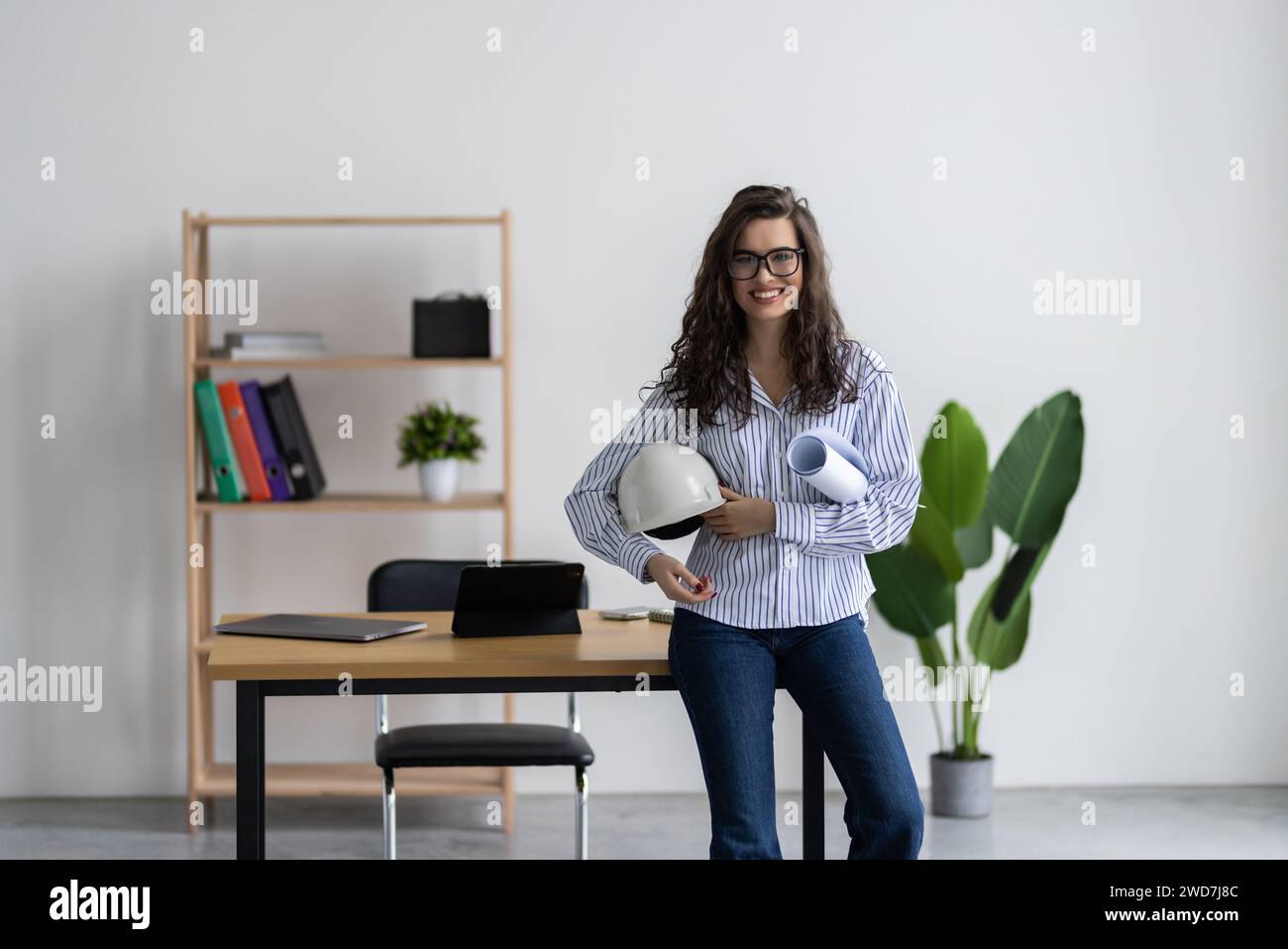 Caucasian young female architect working with home drawing plan on blue print with architect equipment in the office Stock Photo